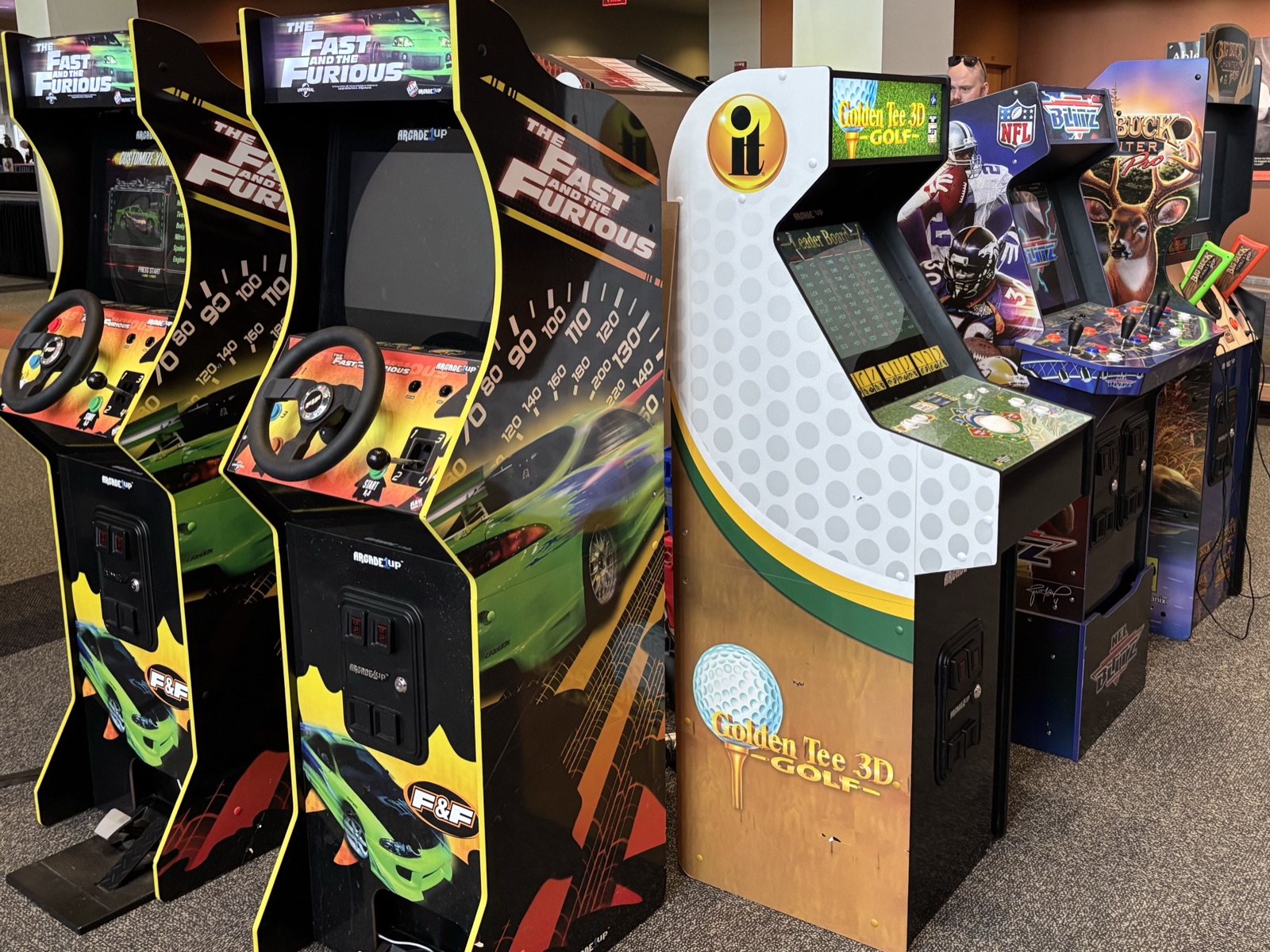 Full-size arcade cabinets lined up: Fast and the Furious, Golden Tee, NFL Blitz, Big Buck Hunter
