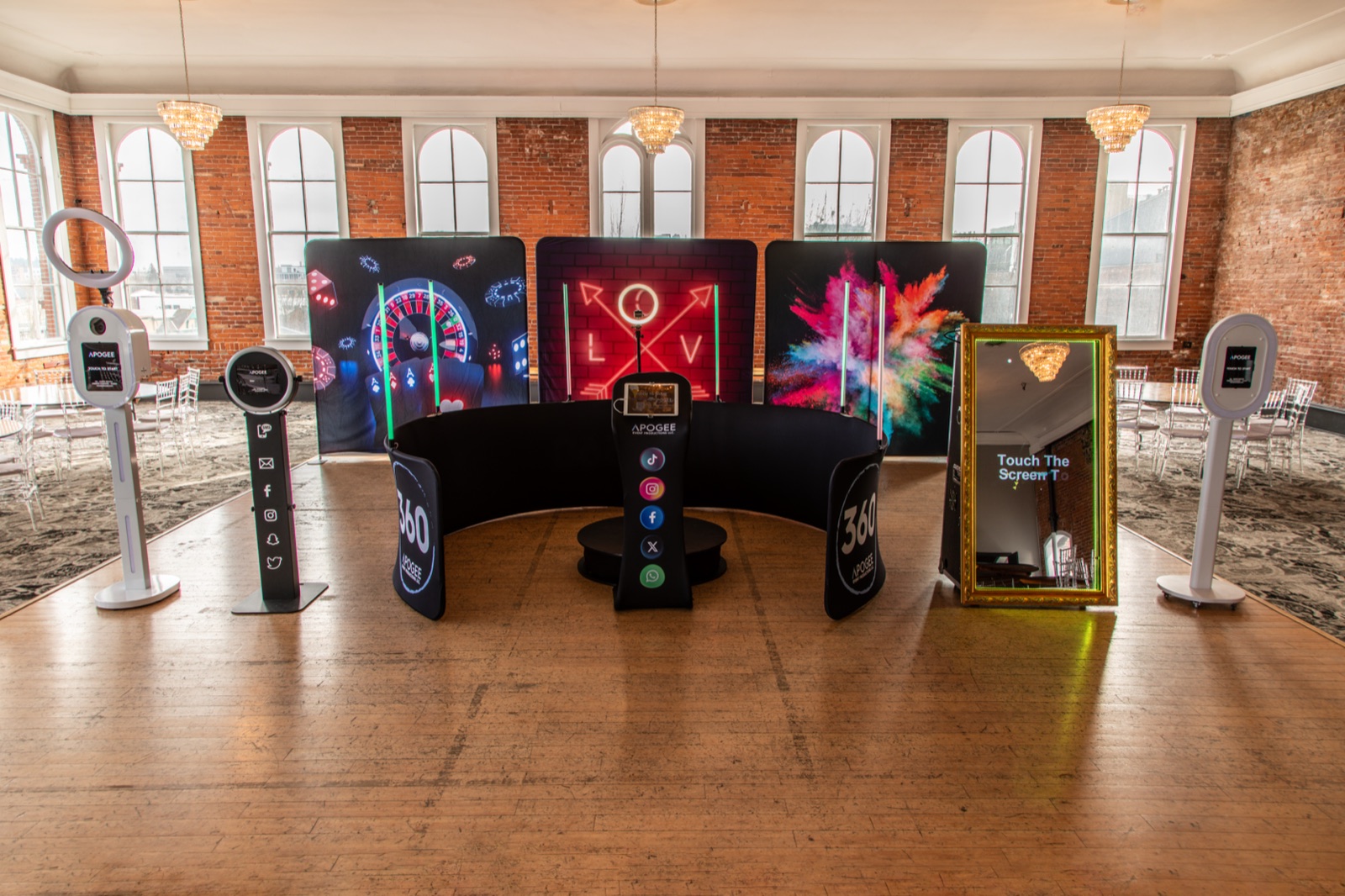 Apogee photo booths lined up on the Reed Ballroom floor: ring-light booths, backdrops, the 360 enclosure, and the gold Magic Mirror under brick arches