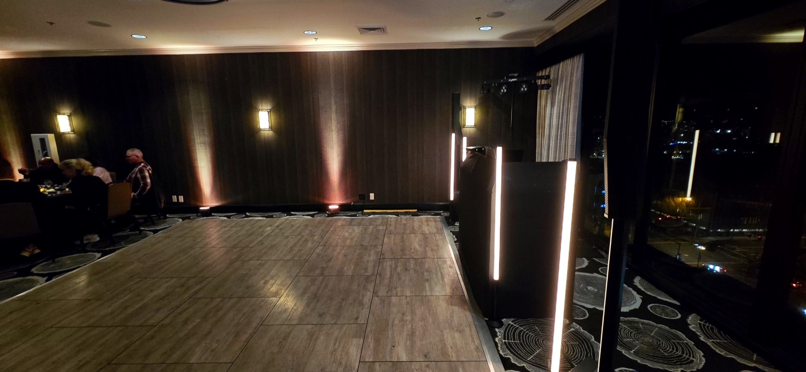 Empty dance floor at The Graduate in Eugene with amber uplighting, glow bars, and a DJ booth by the window