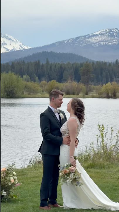 Couple at the water's edge at Black Butte Ranch with the Cascades behind them