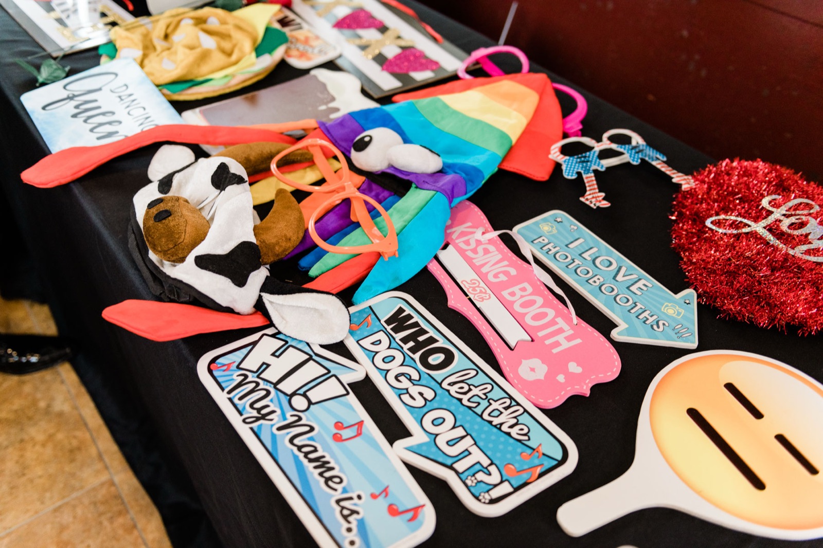 Photo booth prop table with signs, hats, and oversized glasses at Green Villa Barn wedding