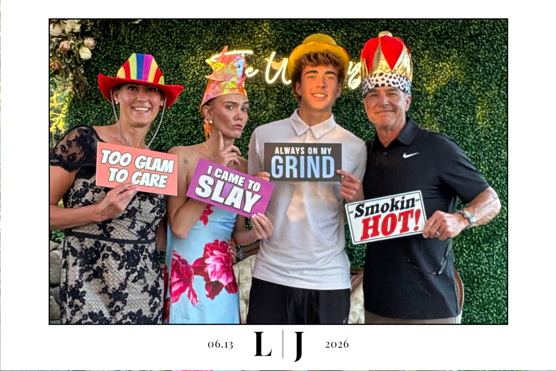 Four wedding guests pose with colorful signs in a full-width Queen photo booth print from Silverton, Oregon
