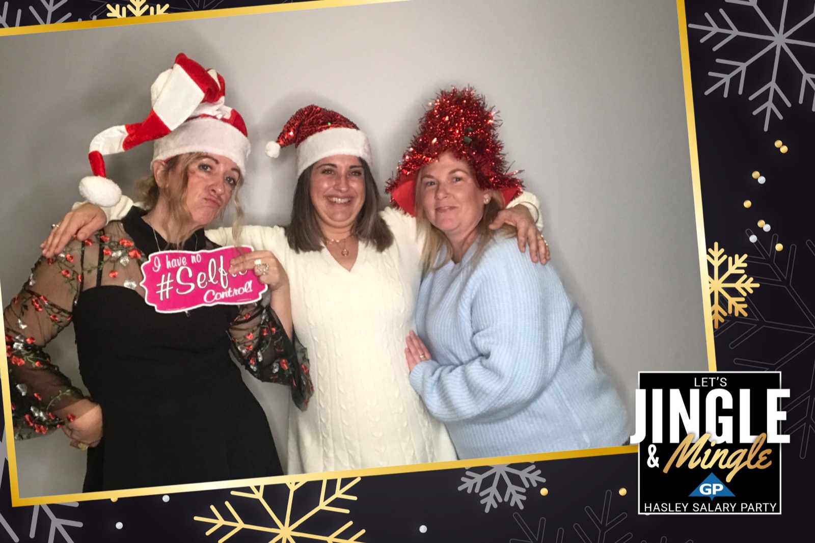 Holiday photo booth print of three coworkers in Santa hats with a selfie prop sign, Jingle and Mingle border