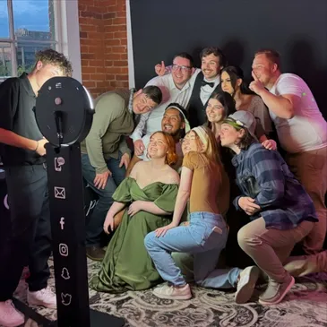 Kayden running a photo booth as a group crowds in for a photo