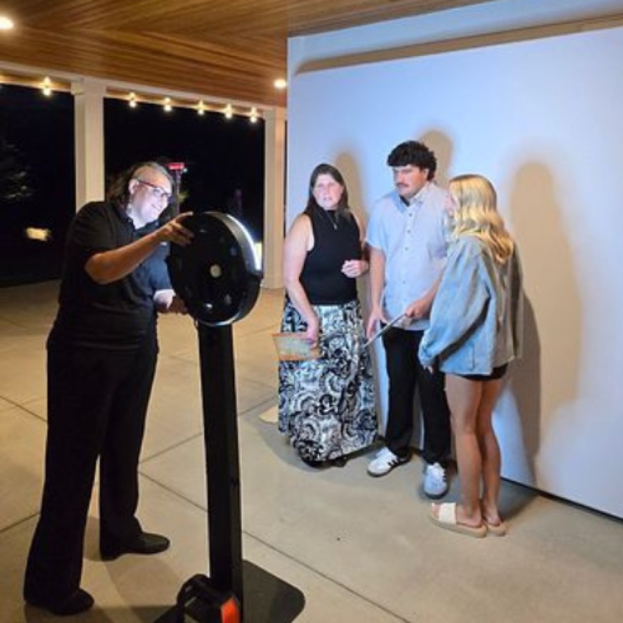 Kelli Nunn setting up a ring-light photo booth while three guests wait to pose