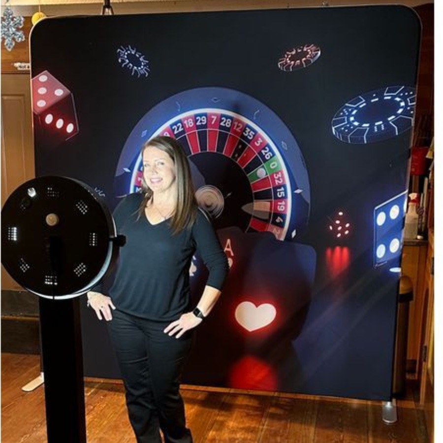 Trisha standing beside a photo booth in front of a casino-themed backdrop