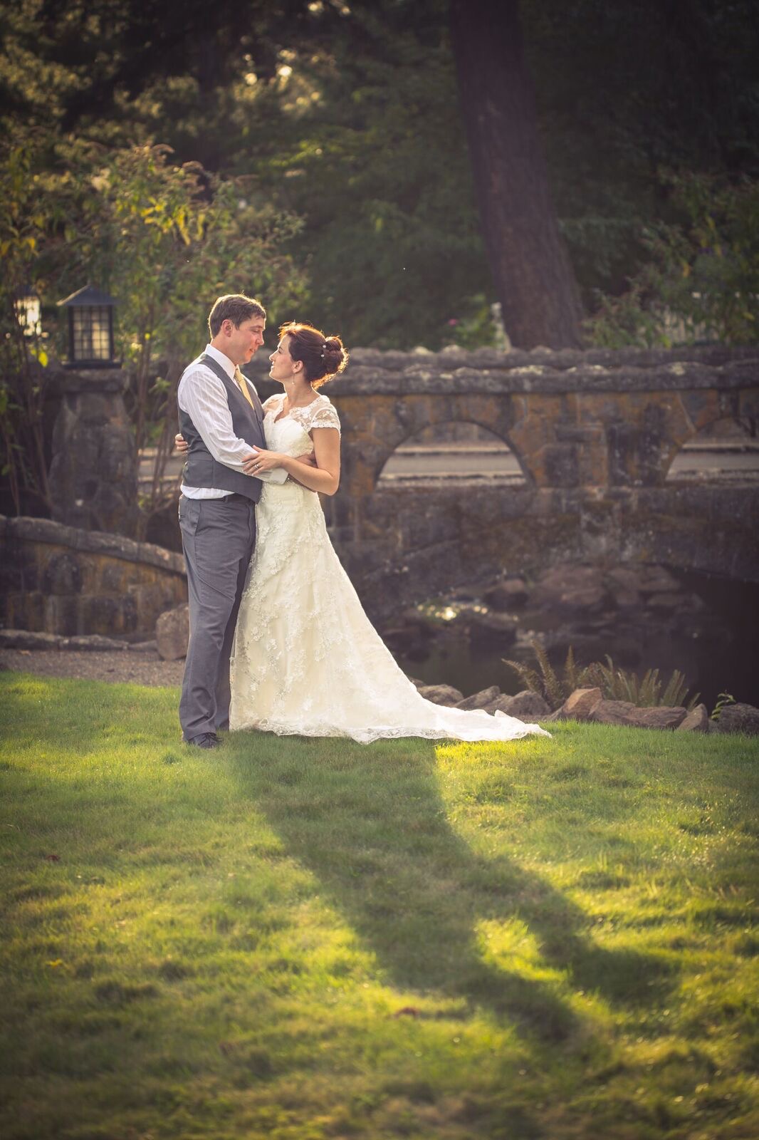 Backlit bride and groom kissing at night on a dock, their silhouettes reflected in dark water